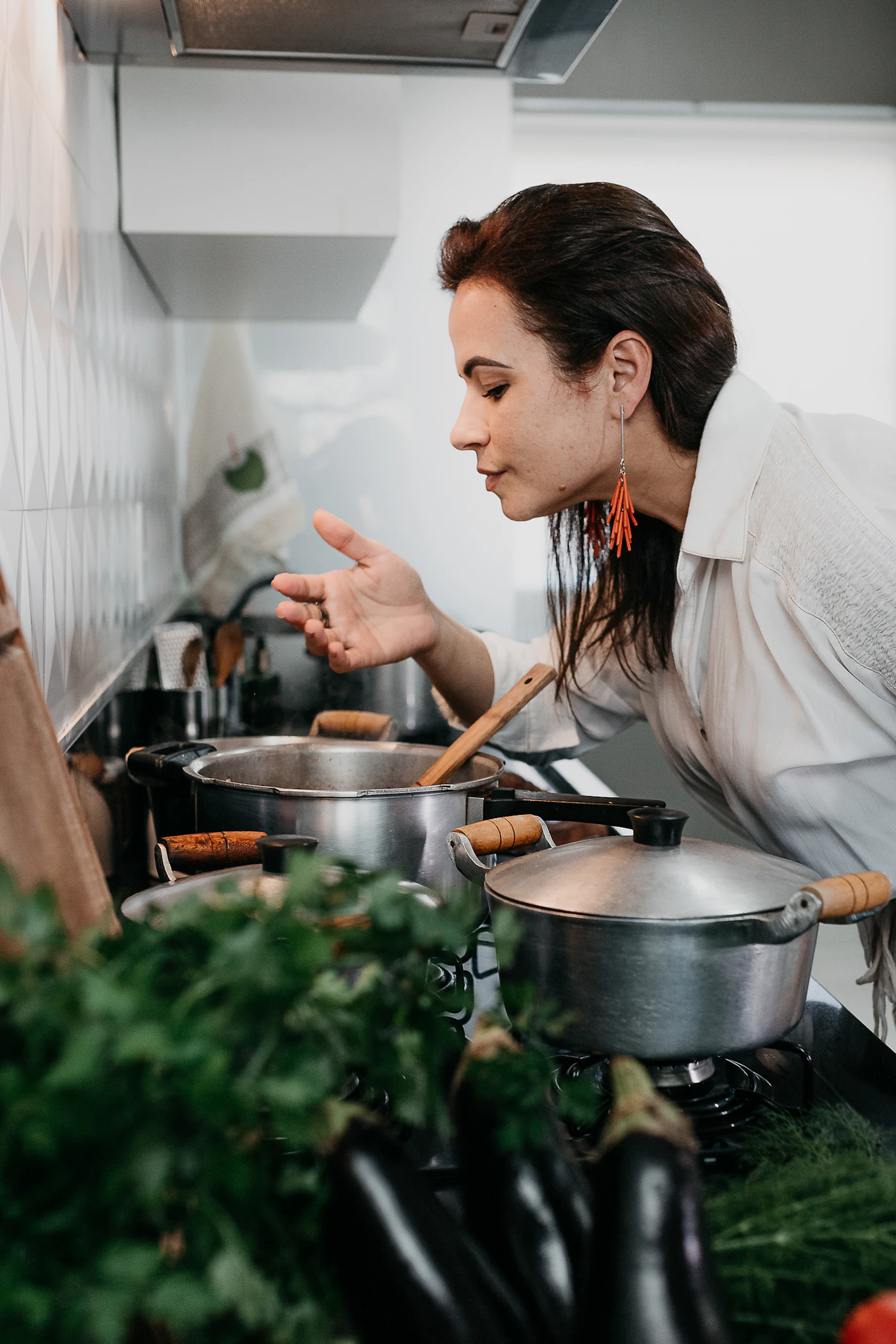 A person eating from a bowl beside cooking pots in a home kitchen