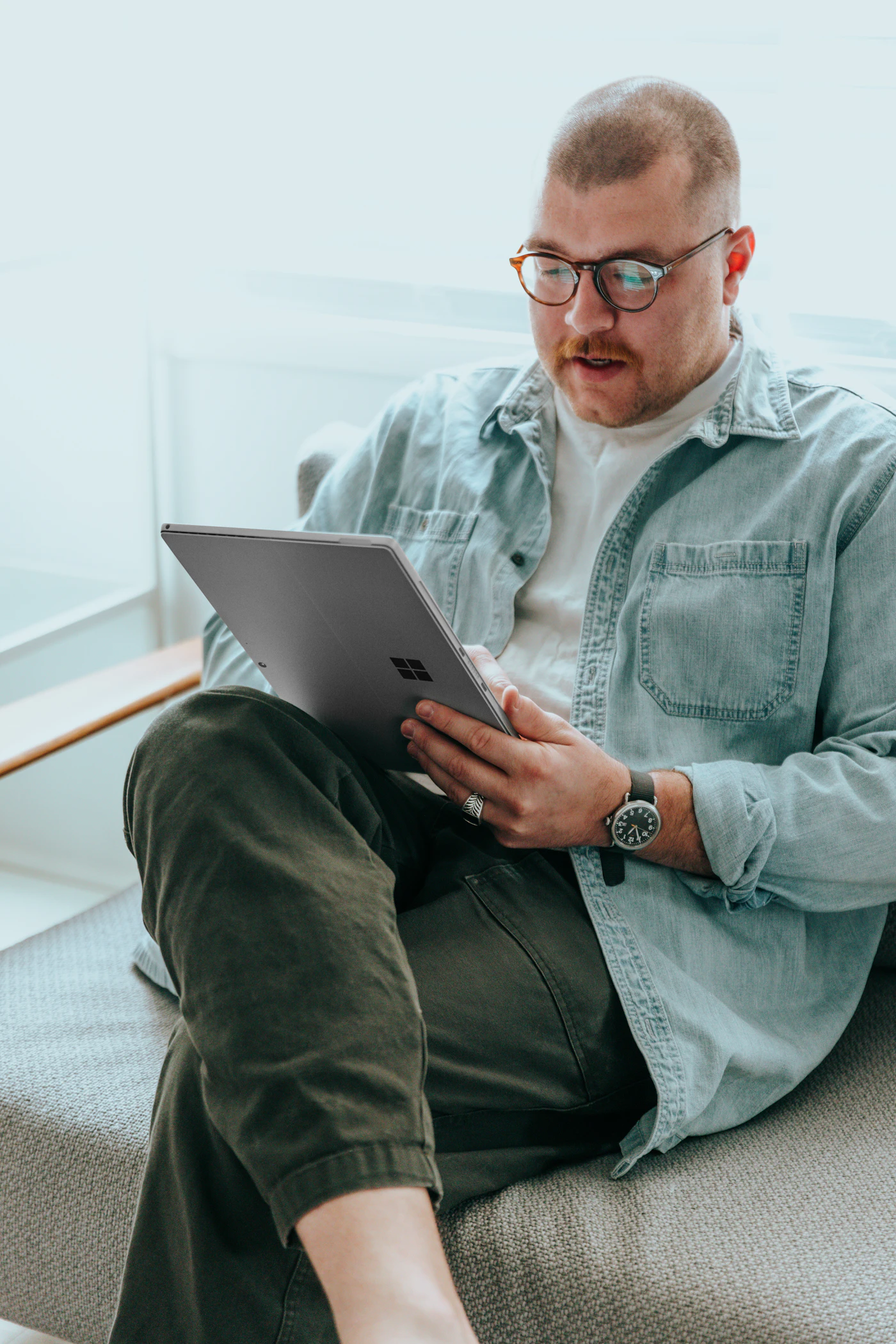 A person seated on a sofa using a tablet